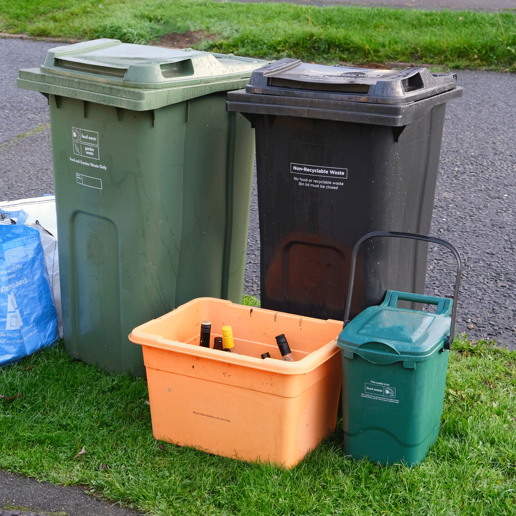 Recycling wheelie bins outside a fence