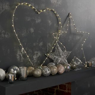 black textured wall and fireplace and baubles and metalic star and heart shape