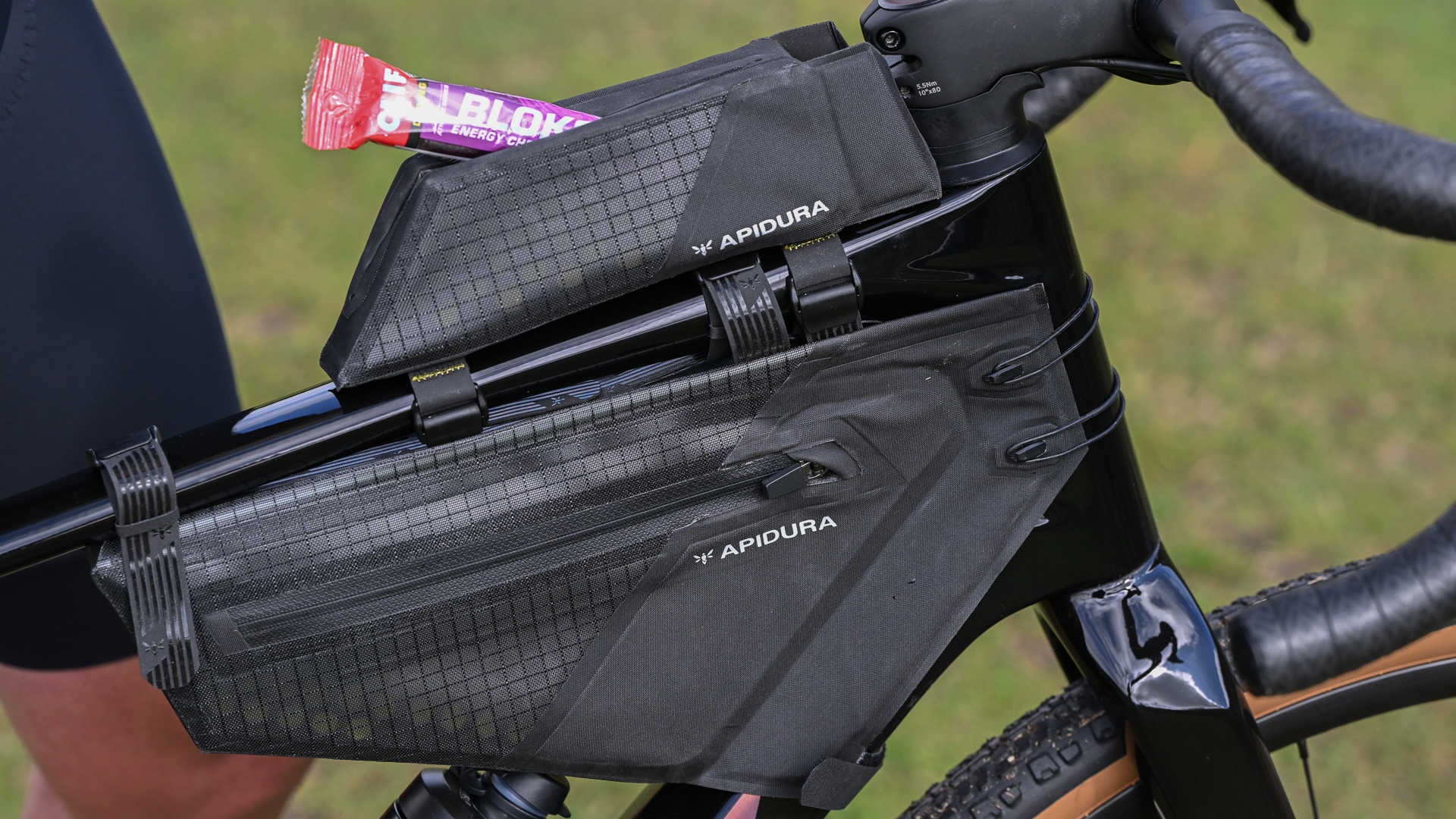 close up of a black top tube bag and frame bag on a black bike, with a packet of Shot Bloks sticking out of the top tube bag