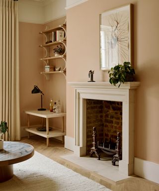 living room with peachy white walls, a fireplace, open shelving and a wooden floor