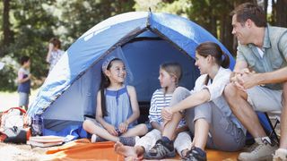 Family of four sitting outside tent