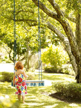 small girl on decorative garden tree swing