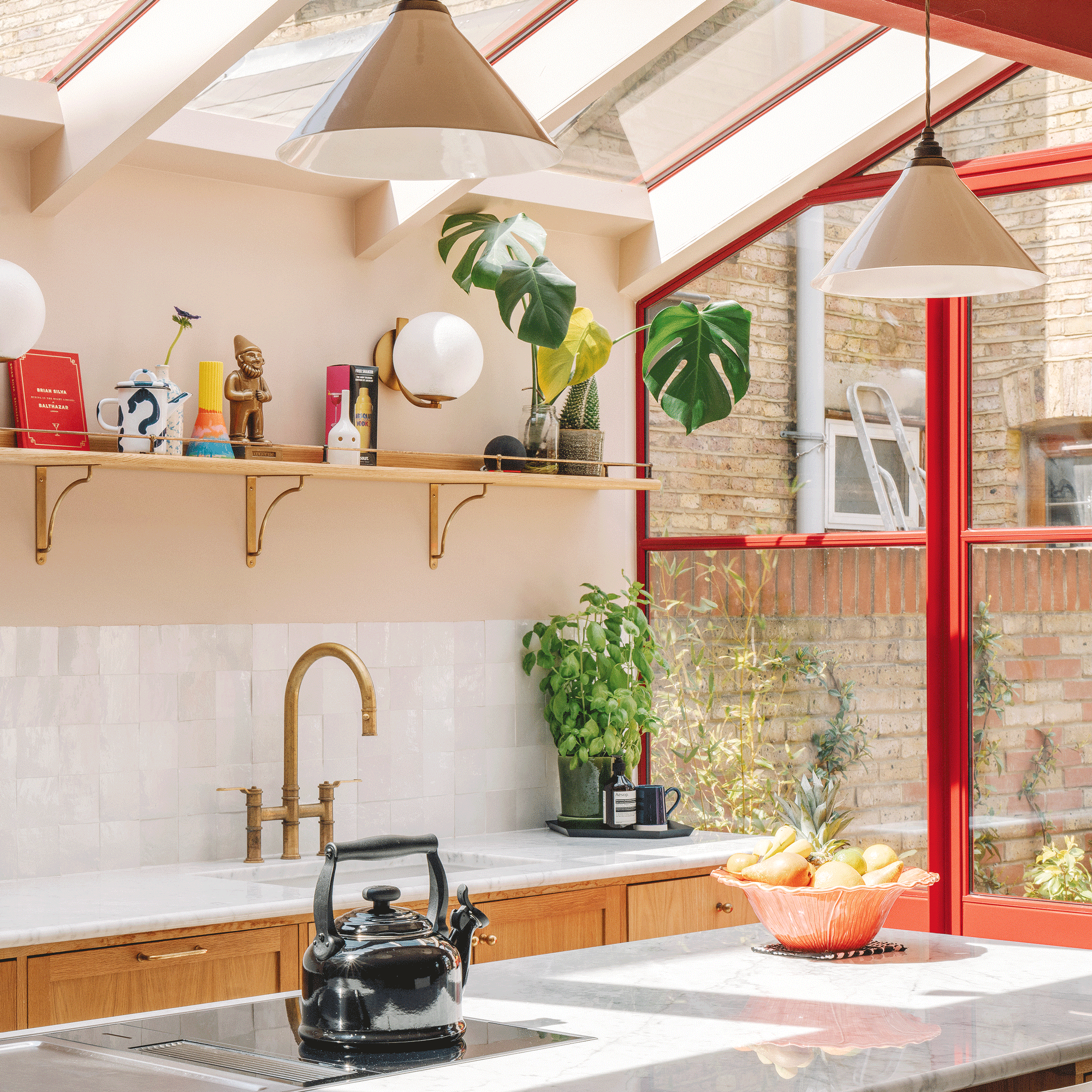 a side return extension kitchen with red framed glazing, a skylight and marble countertops