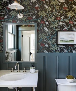 Patterned wallpaper in dark half bathroom with white door with paned glass and frame on the wall