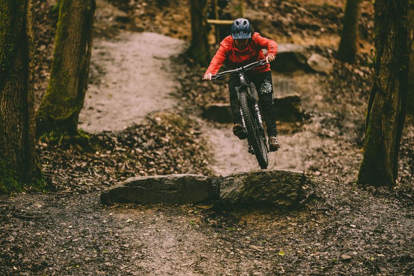 Female mountain biker rides off rock drop