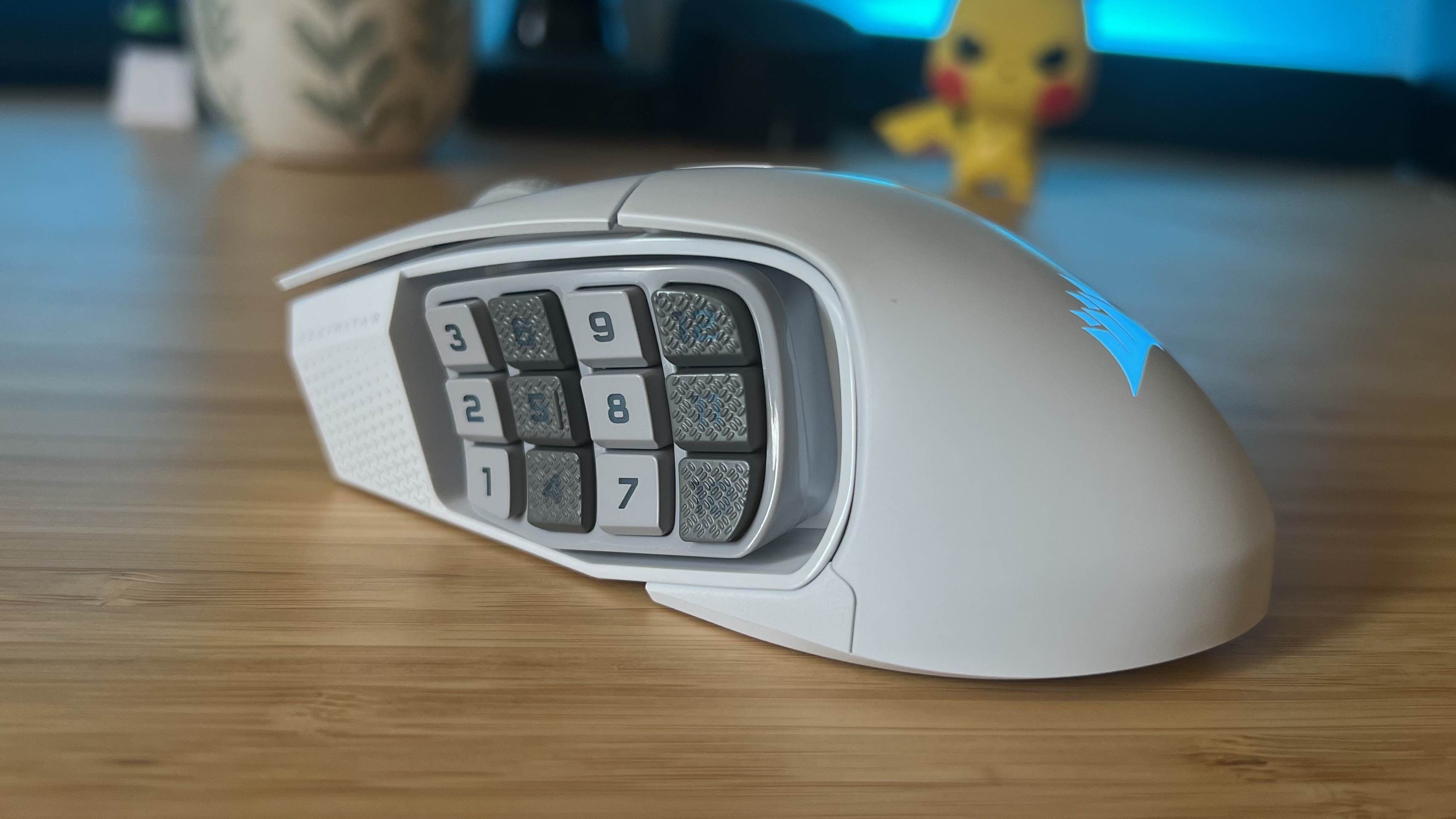 Close up on side buttons of Corsair Scimitar Elite Wireless SE gaming mouse on a wooden desk