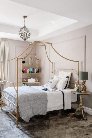 Gold four poster bed in a light pink bedroom