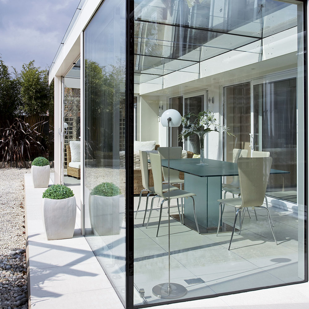 Glass box extension with dining table and chairs inside