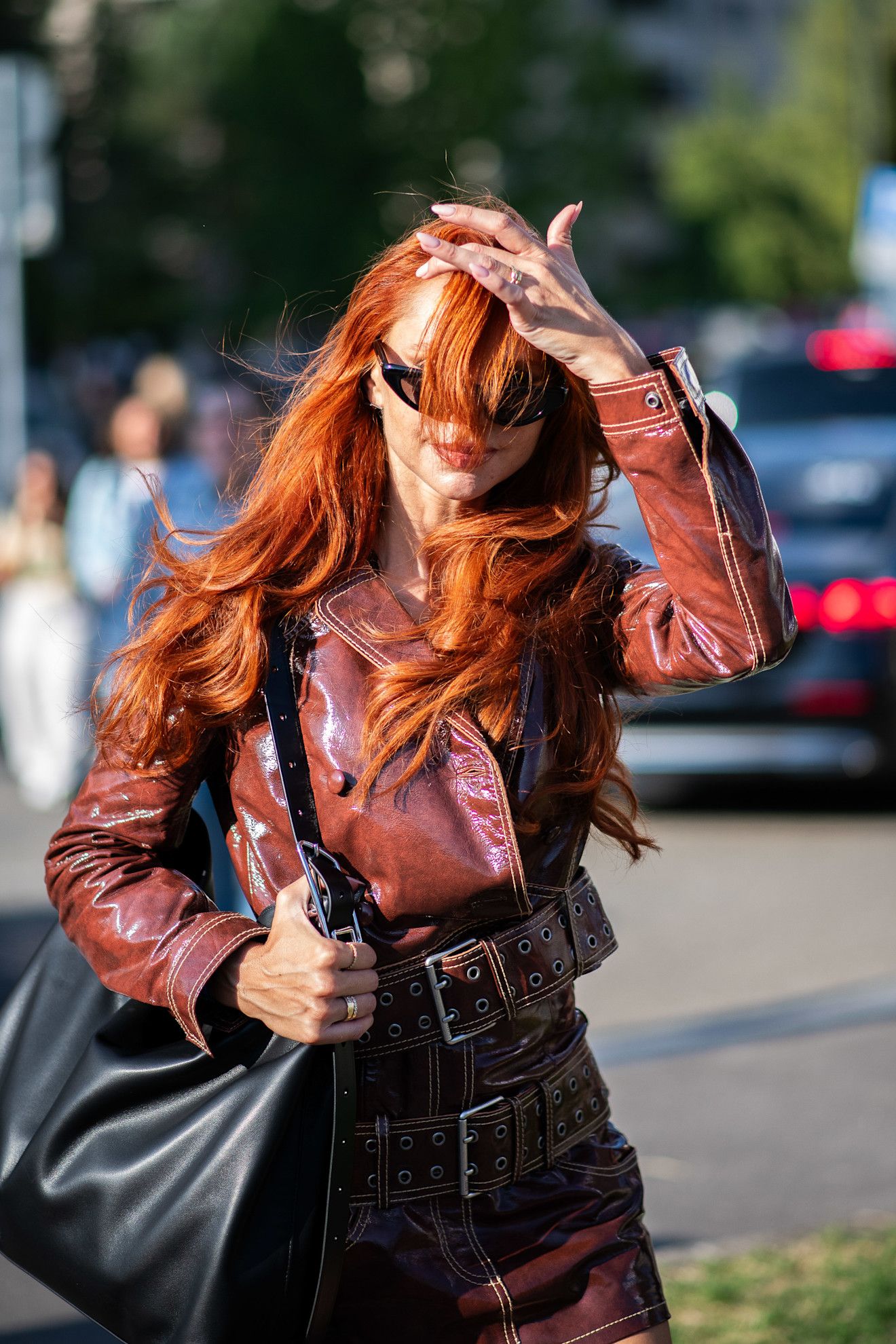a white woman with red hair billowing in front of her face in a red jacket