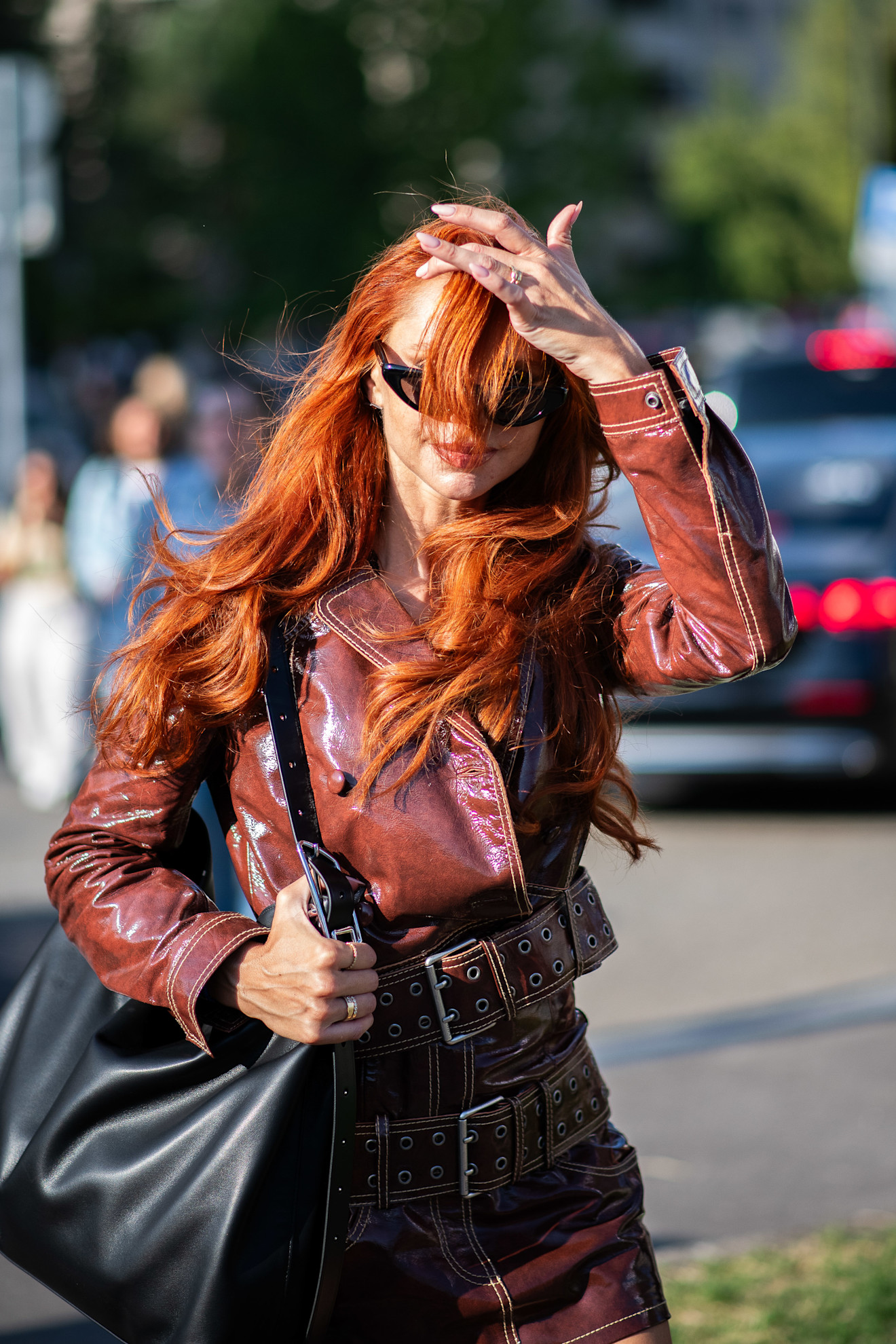 a white woman with red hair billowing in front of her face in a red jacket