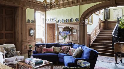 grand georgian panelled wood entrance hall with blue curved sofa and sweeping staircase
