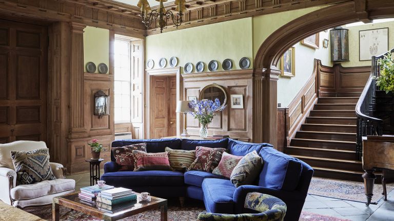 grand georgian panelled wood entrance hall with blue curved sofa and sweeping staircase
