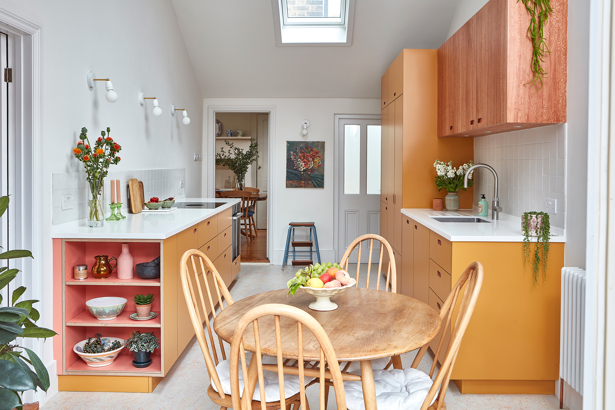 A bright and colorful warm yellow modern kitchen diner with a roof light in the pitched roof
