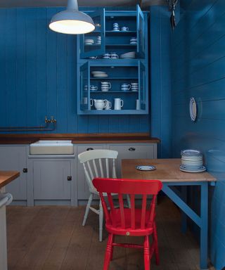 kitchen with blue wall and wooden table with plastic chair