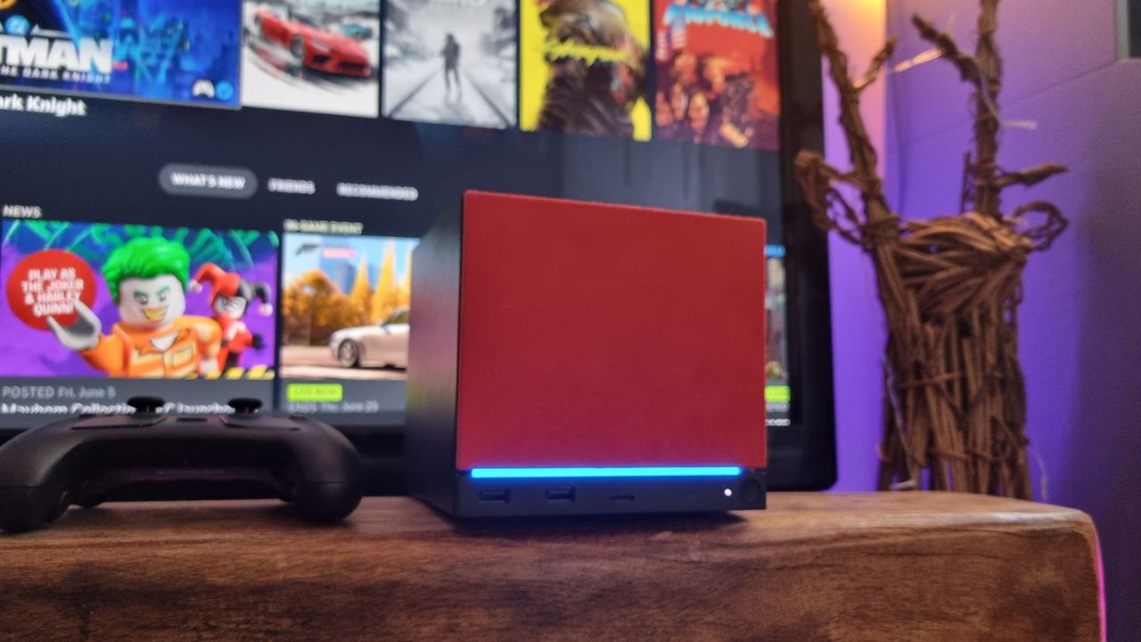 A Steam Machine with a red faceplate attached, in front of a TV