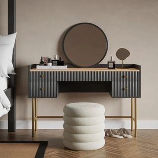 An image of a dark grey dressing table with fluted front with a soft stool in front of it