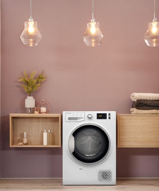 A washing machine appliance in laundry room with trio of pendant light fixtures with pale pink wall decor