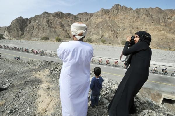 A family in Oman watches the racers pass.