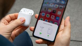 Hender som holder Apple AirPods 2019, ladeetui og iPhone.