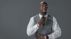 A business man smiles as he straightens his tie.