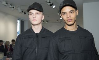 Male models wearing gray modern jackets with black leather hats from A/W 2015 Calvin Klein Collection.
