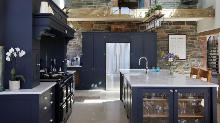 Dark kitchen island and co-ordinated cabinets with sink, marble top and bar chairs