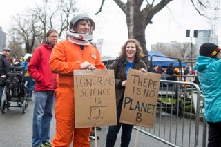 A man dressed as an astronaut holds up a sign at the Science March on the Boston Common on April 22, 2017 in Boston, Massachusetts.