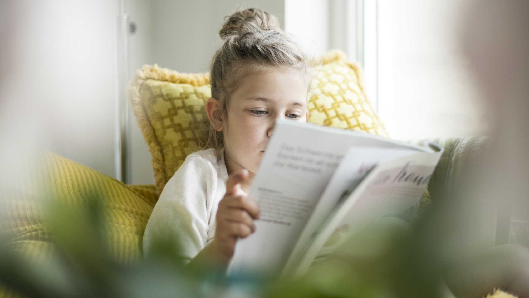 A young girl reads a magazine.