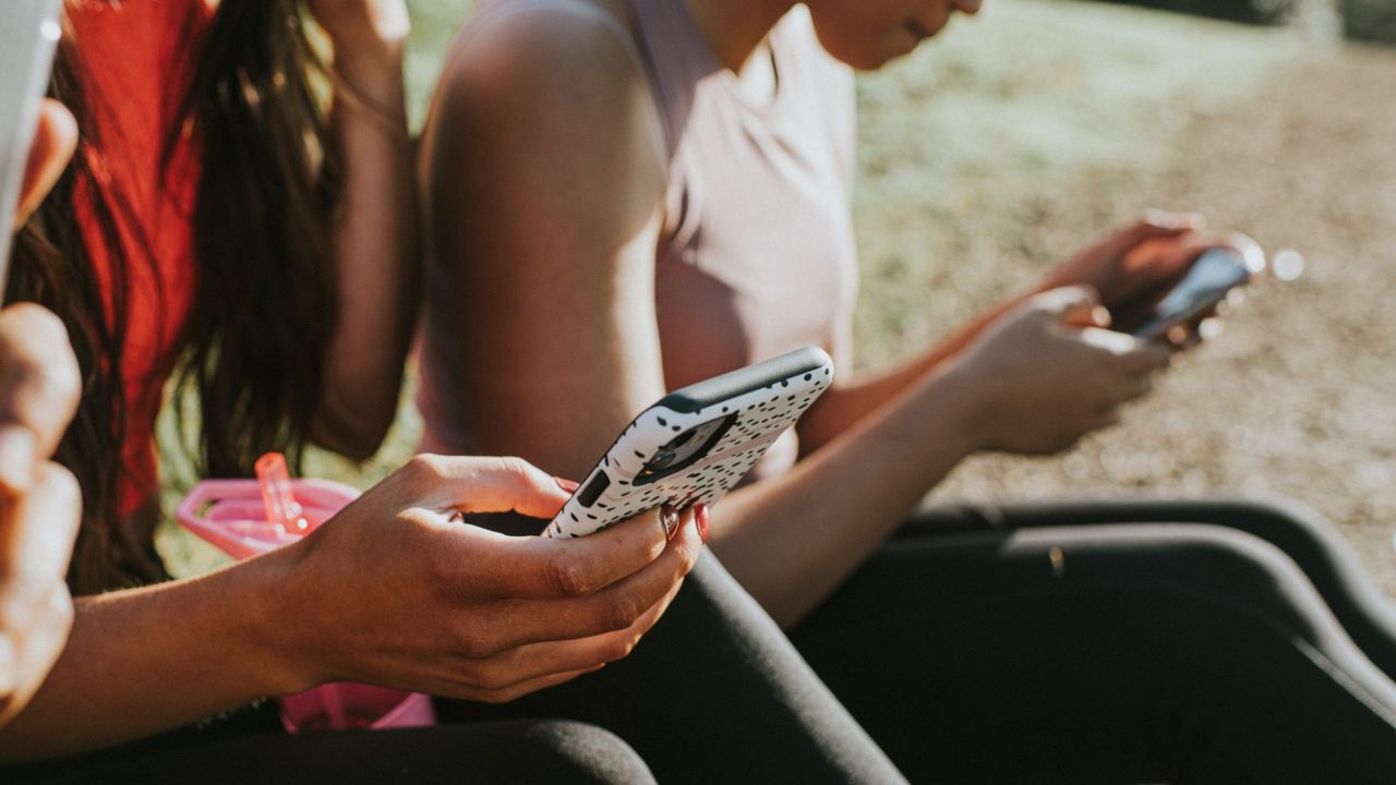 Three woman holding their mobile phones outside and looking at the screens - stock photo