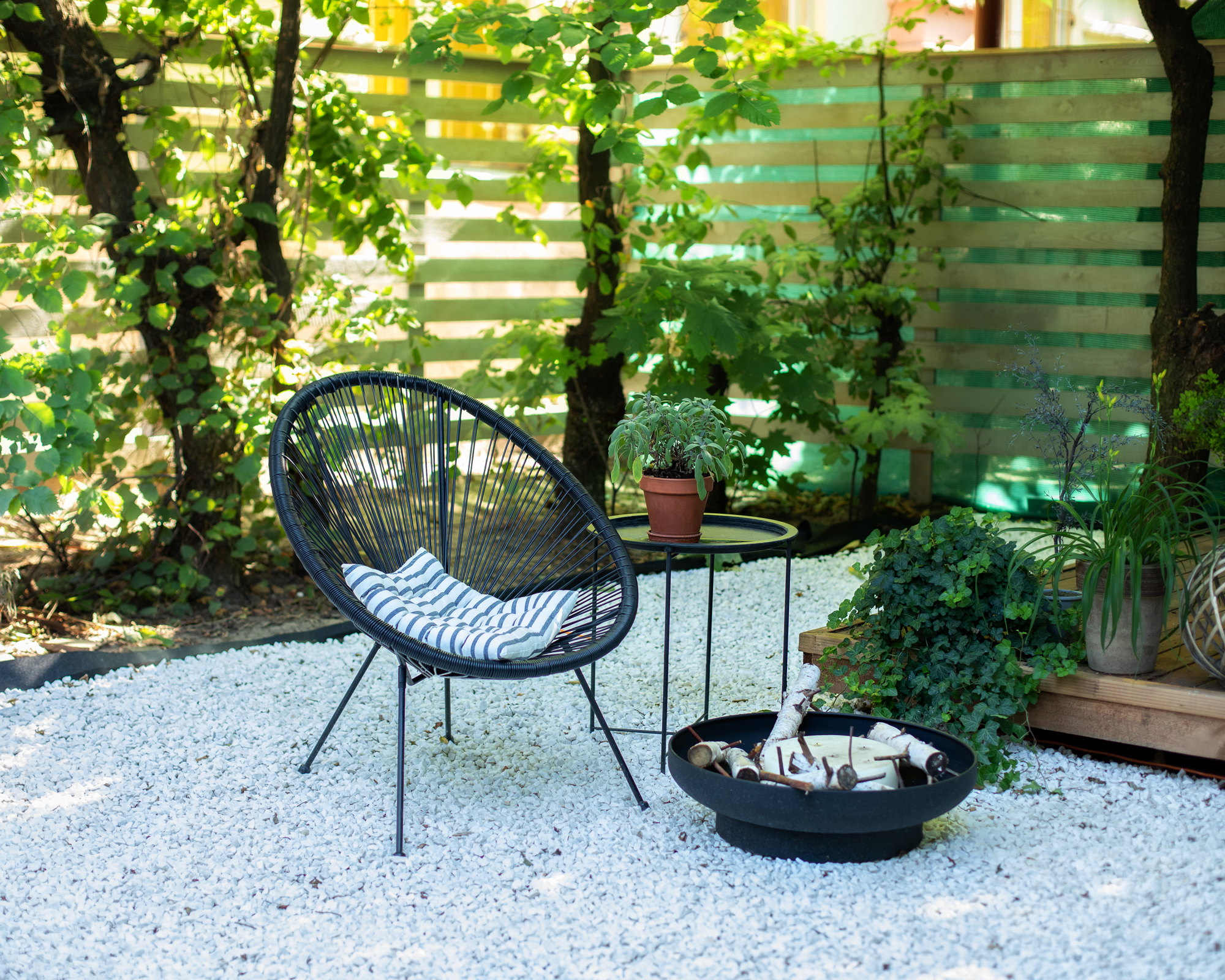 Front veranda of house with black Acapulco armchairs, coffee table and plants pots