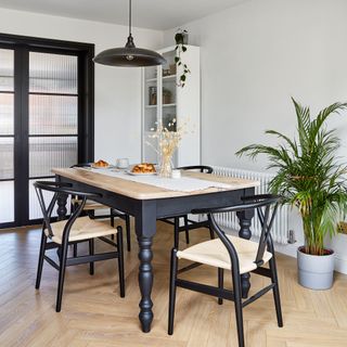 Dining area in open-plan kitchen diner with dark and natural wood coloured dining table and chairs