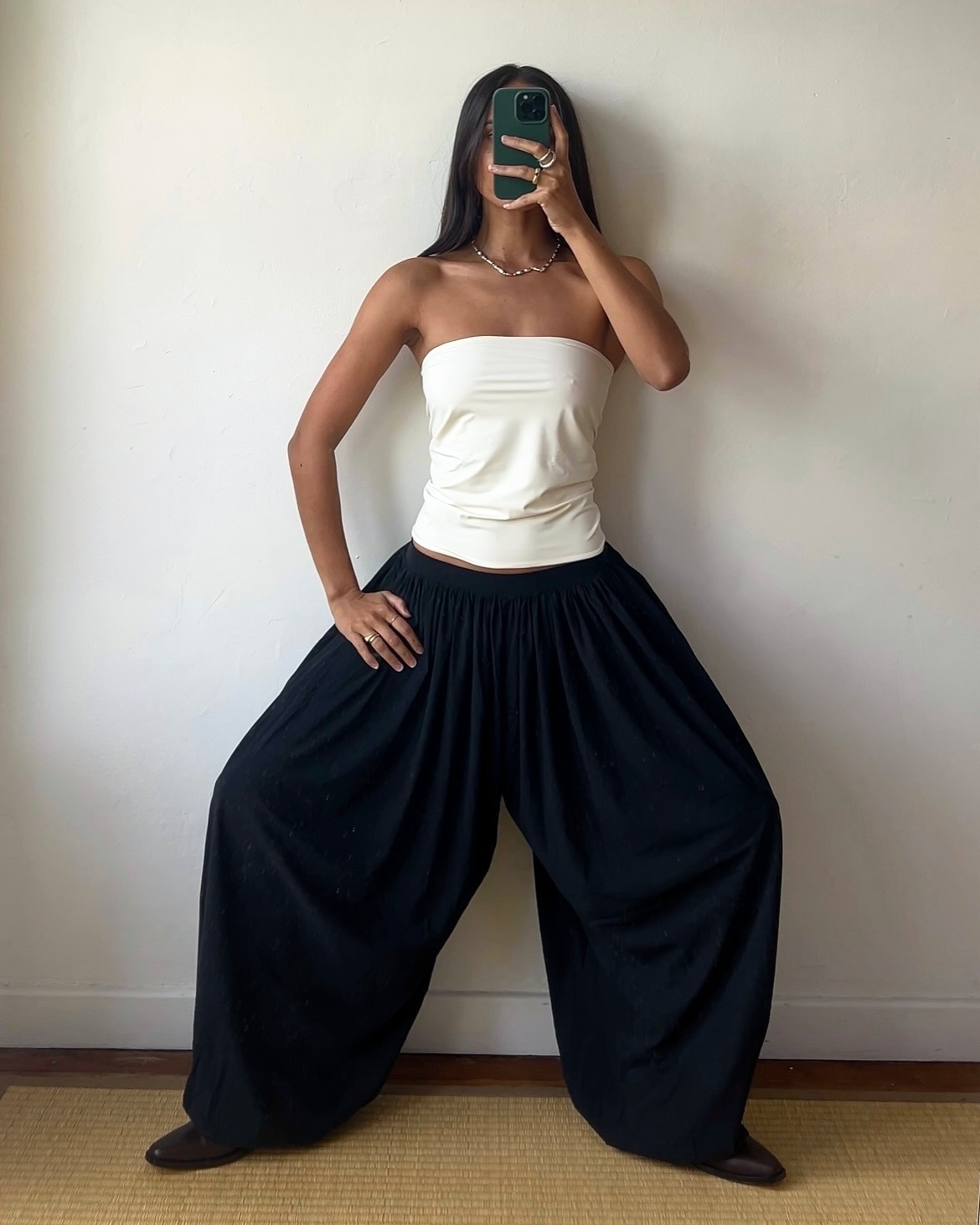 @bellathomas wearing a white strapless top and black Reyem genie pants.