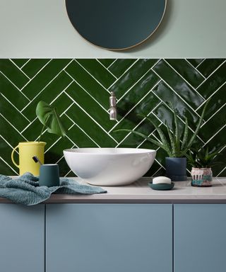 Bathroom basin with green metro tiled splashback in herringbone formation