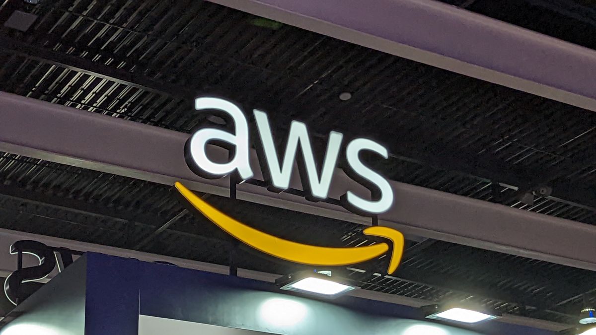 A telephoto shot of the AWS logo on a conference floor, hanging from a beam