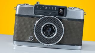 The Olympus Pen EE camera on an orange and grey background