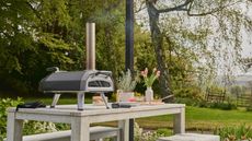 an ooni pizza oven on a wooden table in a countryside setting