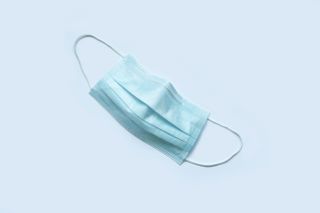 A surgical mask against a grey background. 