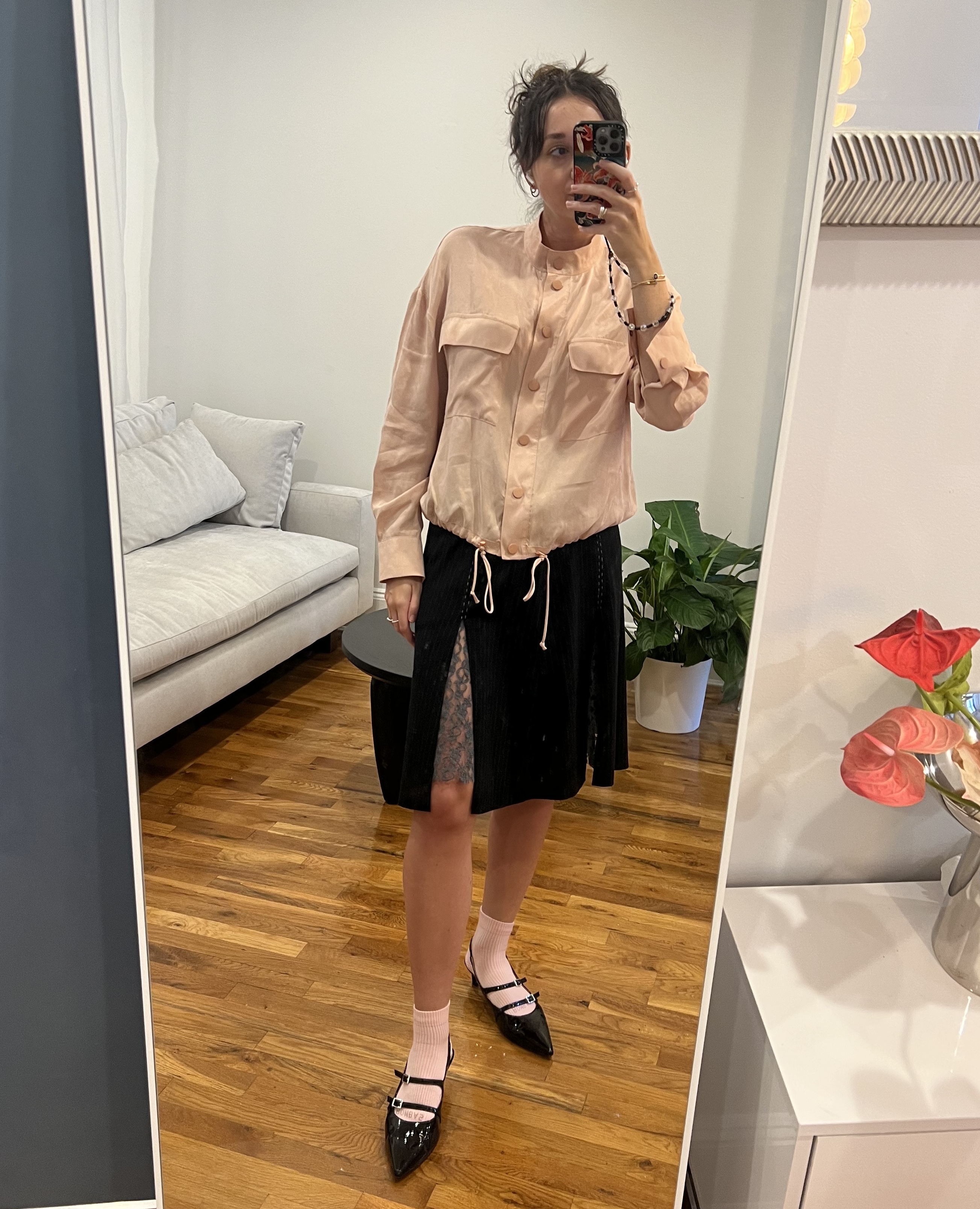 Marie Claire fashion features editor Emma Childs wearing a pink windbreaker jacket, with a black pinstripe skirt with grey lace and black heels