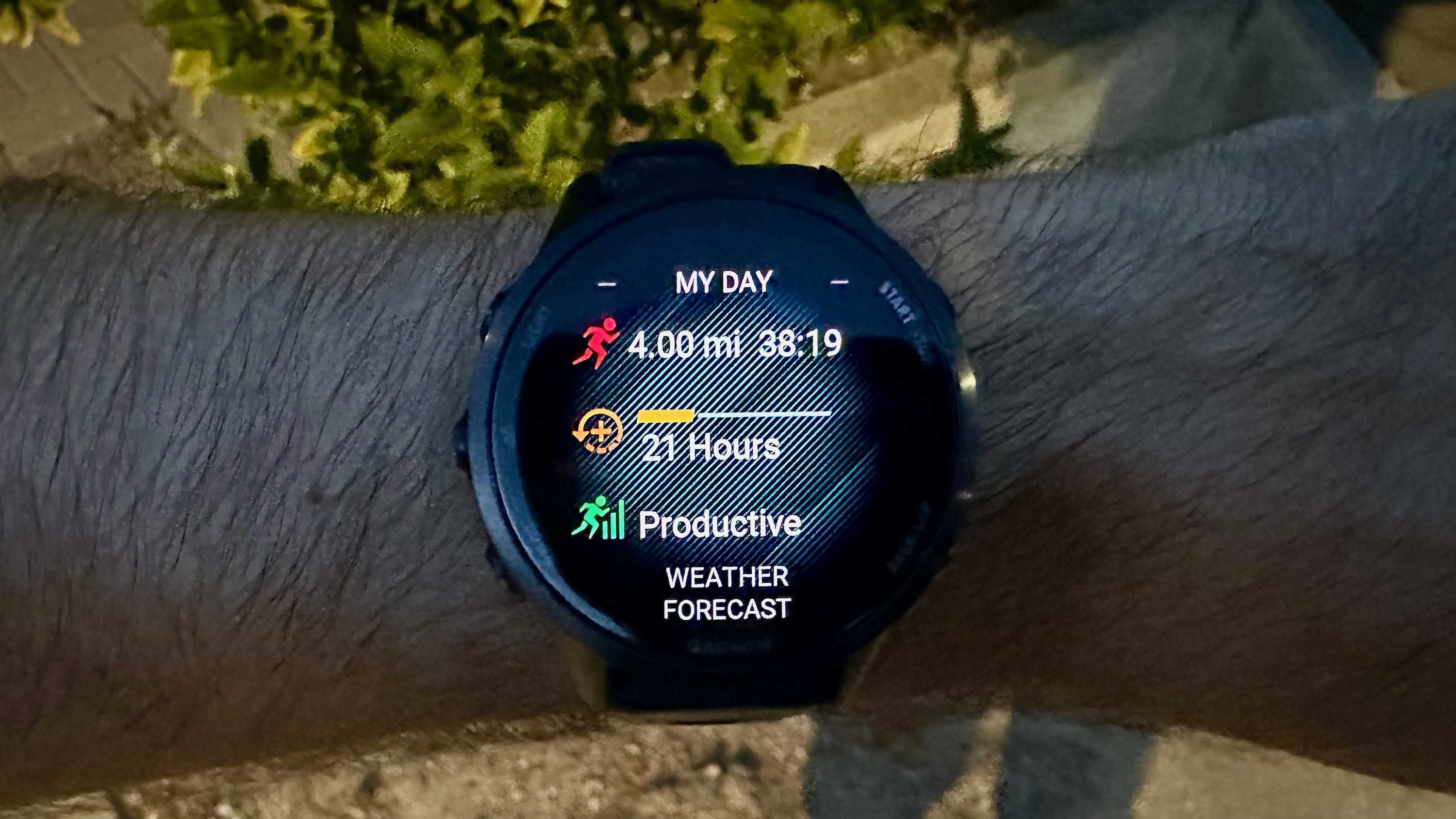 The Garmin Forerunner 970 worn on a wrist in low light, showing "My Day" data like the author's run, recovery time, Training Status, and Weather Forecast.