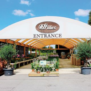 Entrance to a Hillier garden centre with blue sky behind and plants lining the pathway