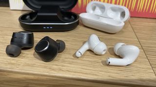 Cambridge Audio Melomania M100 vs AirPods Pro 2 with their charging cases on a wooden table