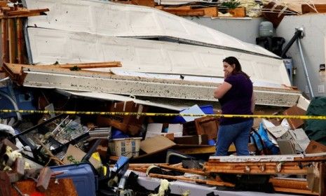 April Bridges pauses while digging through the remains of a home destroyed by they half a dozen tornados that ripped through north Texas Tuesday.