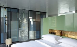 Casa Fayette bedroom with Mondrian-esque mirrors and obscure glass in aluminum frames separating bathroom