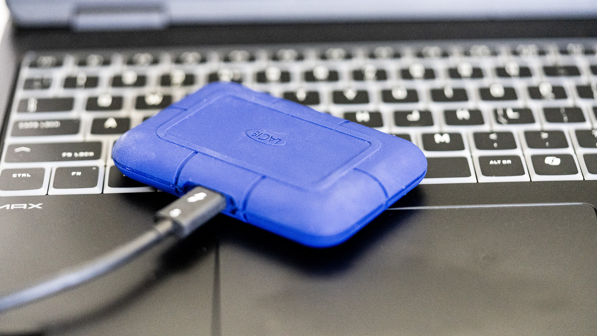 The LaCie Rugged Pro 5 in blue on a laptop and on a white background.