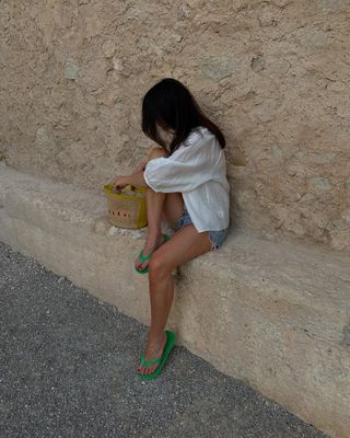 @francescasaffari wearing denim shorts, white linen shirt and green flip-flops