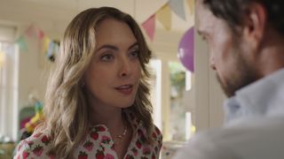 Claire and Byron talk at home. In the background you can see their sunlight home set up with balloons and streamers for a child's birthday party.