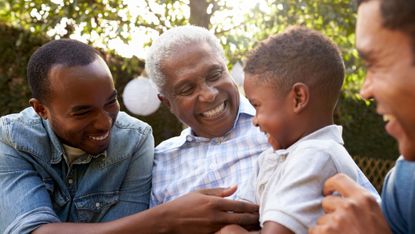 Close up of happy grandfather, sons and grandson in a garden