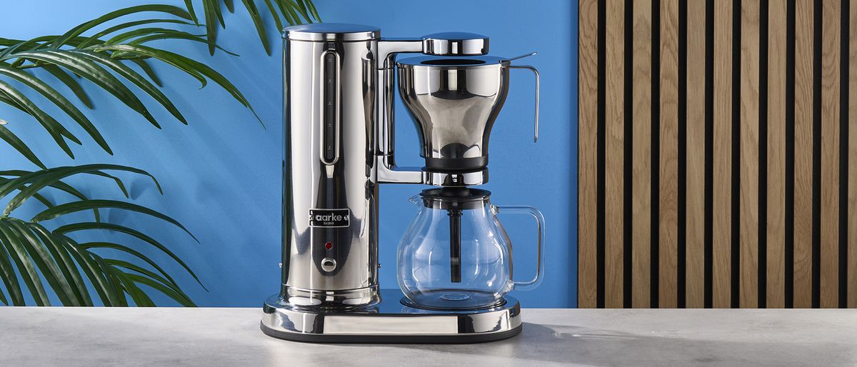 a silver drip brew coffee maker with a 10 cup capacity is photographed against a blue background