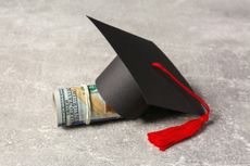  Graduation cap and banknotes on a light grey table