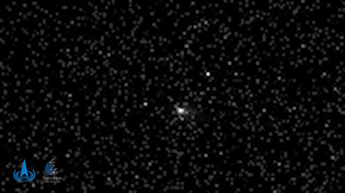 black and white gif of a comet, seen as a blurry white orb, moving in deep space, with fuzzy and distant stars all around